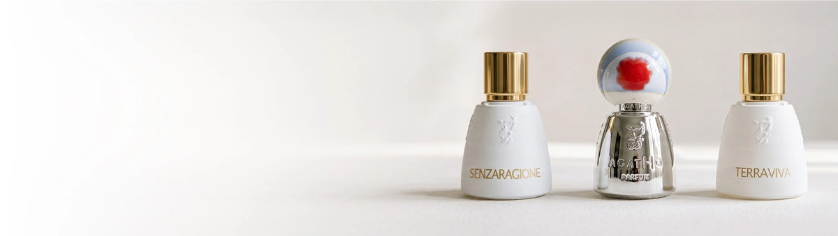 Agatho perfume bottles Senzaragione and Terraviva, white with gold caps, and a silver one with a red flower cap, on white